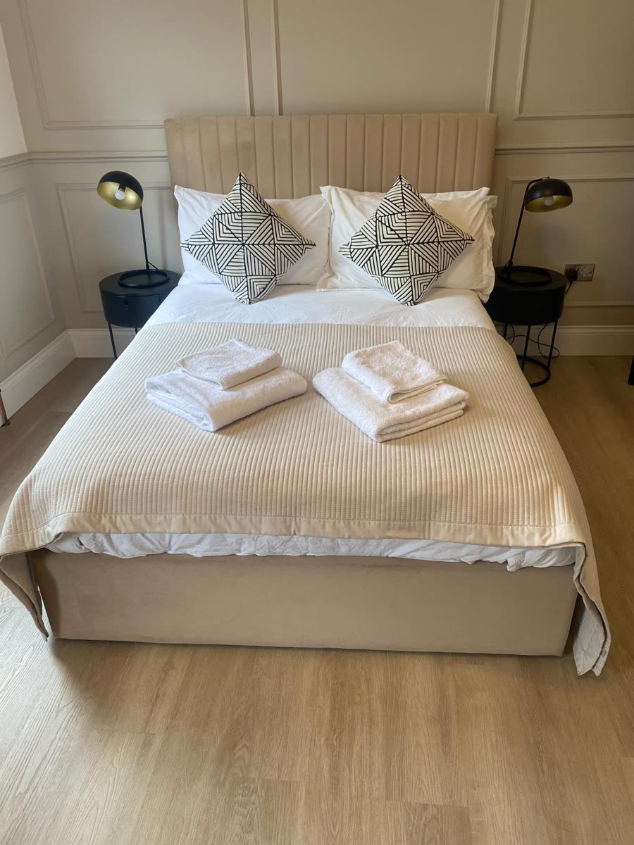 Short-let bedroom made up with fresh white linen and folded towels for the next guest