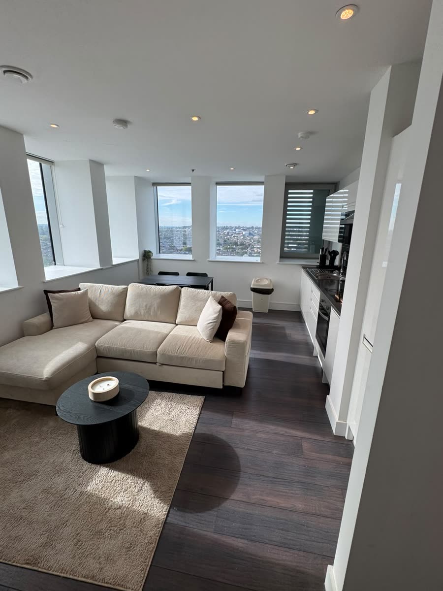 Open-plan living room with corner sofa and kitchen, cleaned and tidied